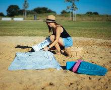 Laden Sie das Bild in den Galerie-Viewer, Frau steckt aufblasbares Kopfkissen in graues Strandtuch 190 x 90 cm am Strand
