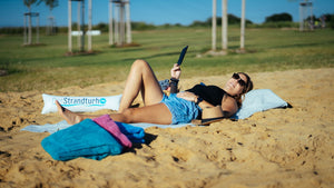 Frau liegt auf grauem Strandtuch 190 x 90 cm mit aufblasbarem Kopfkissen am Strand