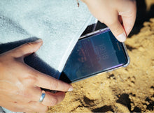 Laden Sie das Bild in den Galerie-Viewer, Smartphone in eingenähter Tasche im grauem Strandtuch 190 x 90 cm

