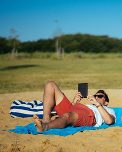 Mann liegt auf blauem Strandtuch 190 x 90 cm aus 100% Baumwolle am Strand