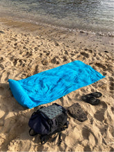Laden Sie das Bild in den Galerie-Viewer, Blaues Strandtuch 190 x 90 cm mit aufblasbarem Kopfkissen aus 100 % Baumwolle am Sandstrand ausgebreitet aus dem Onlineshop DasStrandtuch.com
